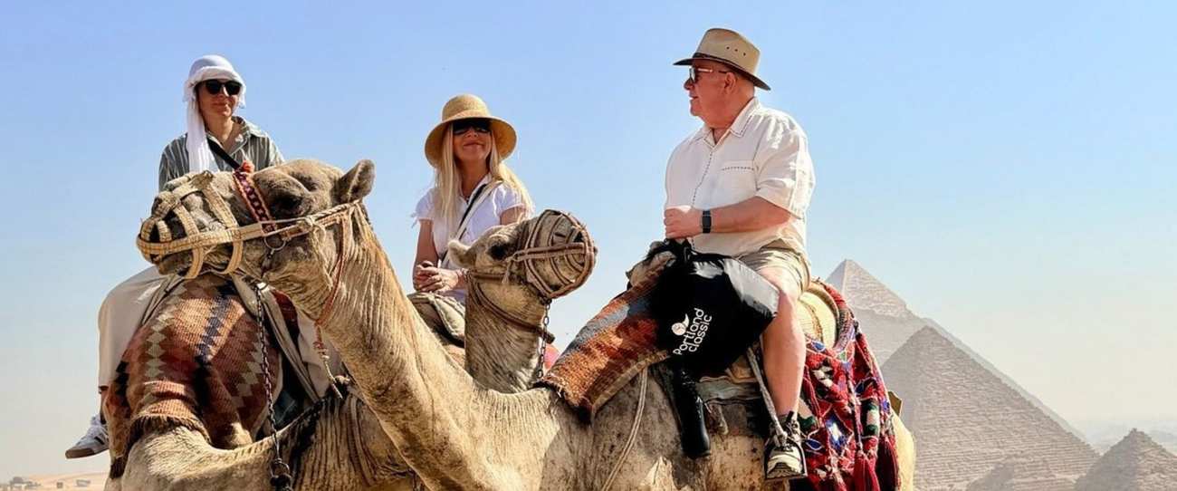 Três viajantes em camelos diante das Pirâmides de Gizé