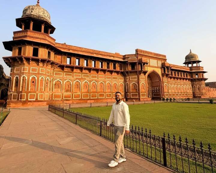 Viajante no gramado diante do palácio de arenito vermelho Jahangiri Mahal, no Forte de Agra, Índia