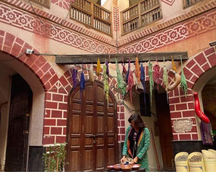 Viajante preparando especiarias no pátio de um riad enfeitado com lã tingida em Marrakech