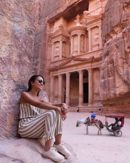 Viajante sentada nas rochas diante do Tesouro de Petra, na Jordânia