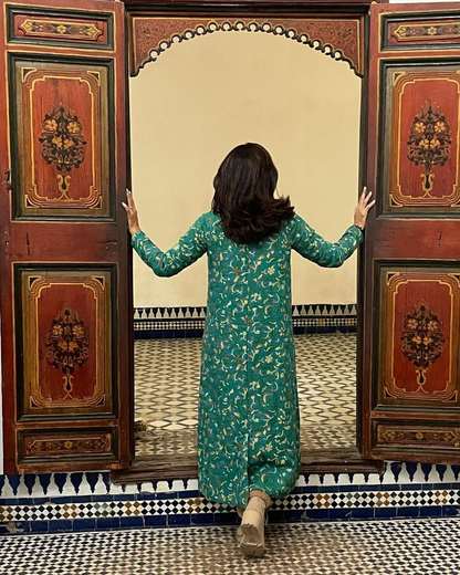 Viajante abrindo portas de madeira pintada para um pátio revestido de azulejos em Marrakech